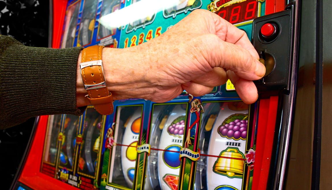 Ein Mensch vor einem Spielautomaten in einem Casino.