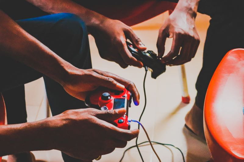 Freunde sitzen auf Stühlen und duellieren sich in einer Partie Fifa 21.