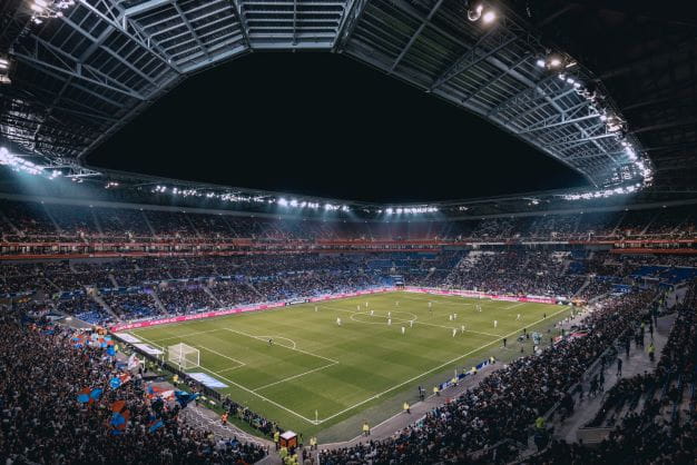 Ein Fußball-Spiel im Stadion bei Nacht vor voller Zuschauer Kulisse.