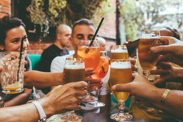 Freunde trinken in einem Gastro-Betrieb gemeinsam Bier und Alkohol.