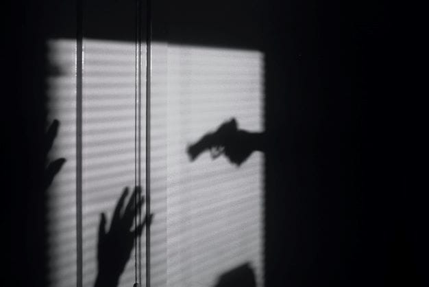 Schatten von Waffe die auf Mann gerichtet wird als Symbol für den Mord-Überfall.