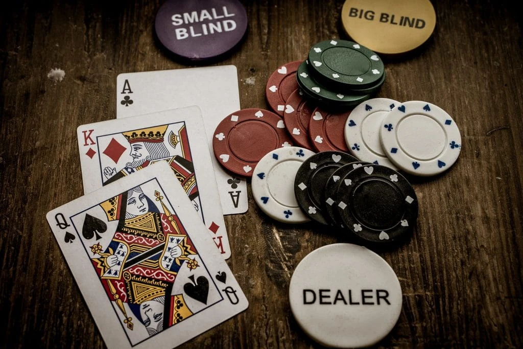 Auf einem Pokertisch liegen verschiedene Spielkarten. Dazu kommen verschieden wertige Chips, so wie die Marker für Dealer, Small und Big Blind.