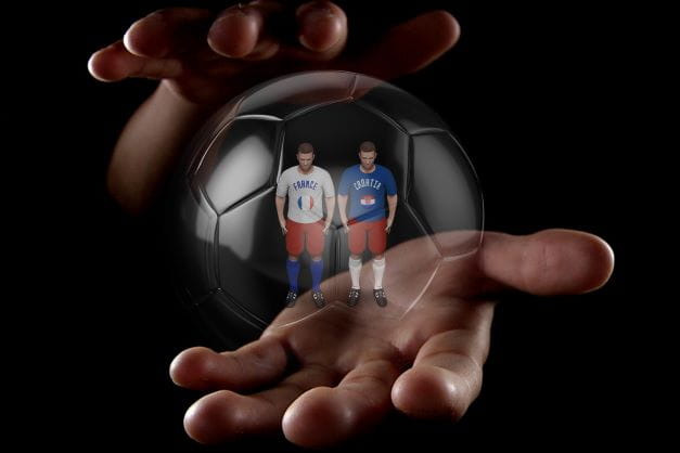 Zwei Figuren aus einem Fußballsimulator stecken in einer magischen Seifenblase, die von einer Hand gehalten wird.