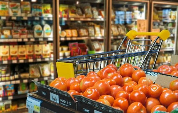 Ein Einkaufswagen steht in einem Supermarkt in der Obstabteilung.