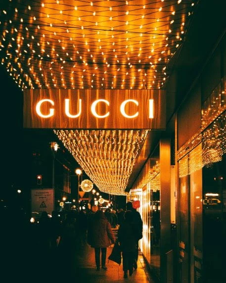 Auf einer Straße erleuchtet eine Reklame des Modehauses Gucci die Dunkelheit.