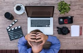 Ein Mann hält sich den Kopf bei Büroarbeiten.