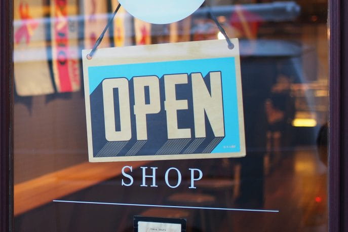 Ein „Geöffnet“-Schild hängt an einer Ladentür.