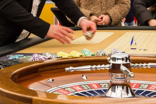 An einem Roulette-Tisch spielen Menschen.