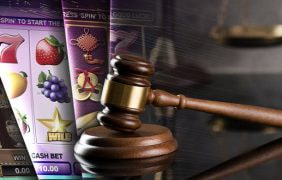 Spielfelder von Online Spielautomaten, daneben ein Richterhammer und eine Waage.