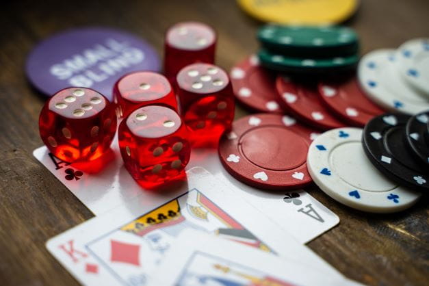 Pokerchips, Würfel und Karten liegen auf dem Tisch.
