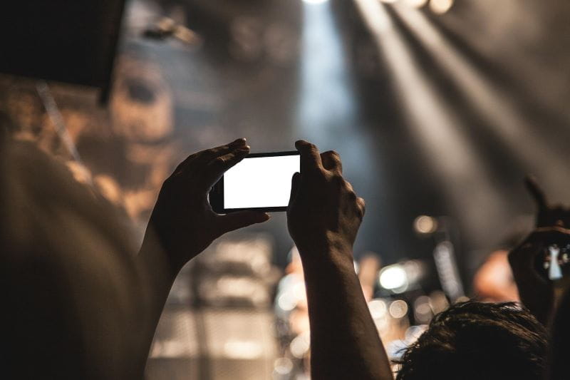 Fans memfilmkan pertunjukan panggung dengan smartphone mereka.