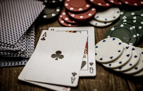 Pokerkarten und Chips liegen auf einem Tisch.