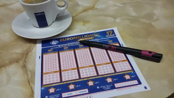Neben einer Kaffeetasse liegen ein Lottoschein und ein Stift.