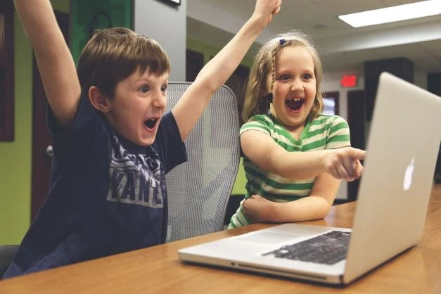 Zwei Kinder spielen an einem Computer.