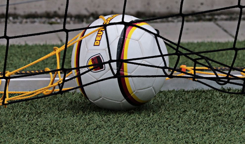 Sebuah bola sepak dengan warna Jerman terletak di jaring gawang.