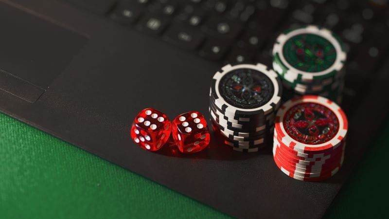 Chip poker dan dadu terletak di laptop.