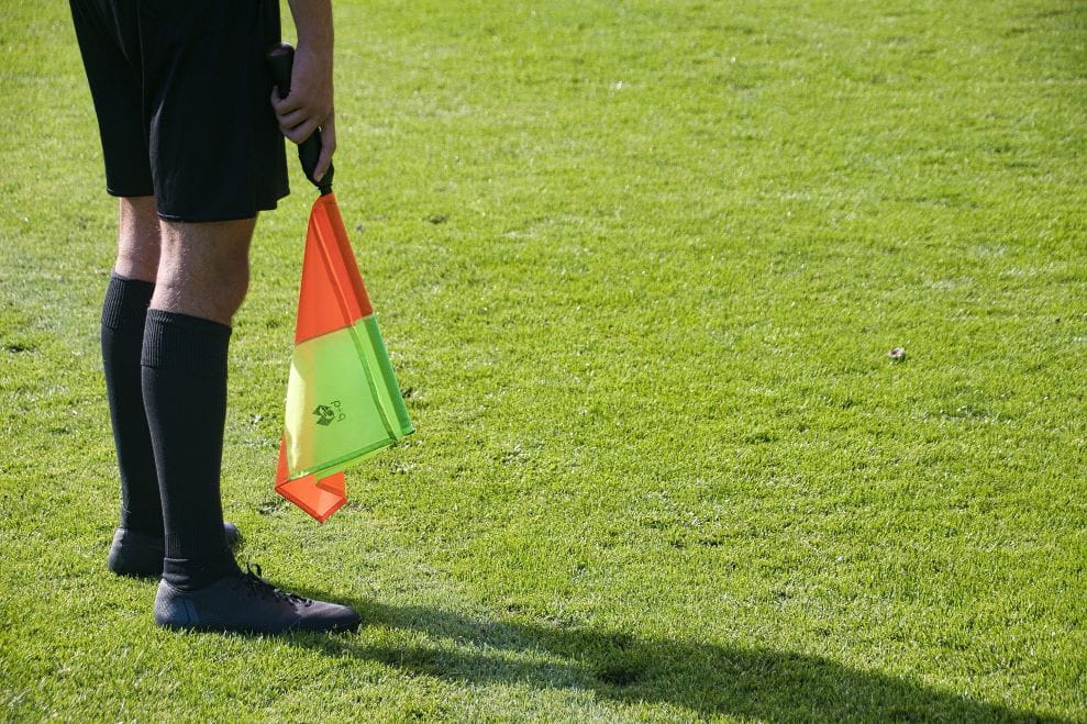 Seorang wasit berdiri di lapangan sepak bola.