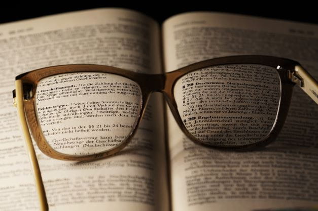Eine Brille liegt auf einem offenen Buch.