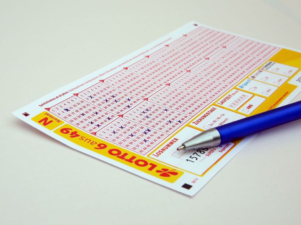 Sebuah pena bersandar pada 6 dari 49 tiket lotre.