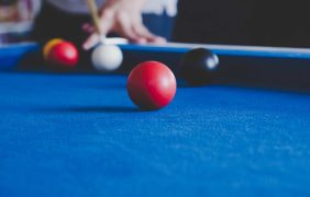 Eine Person stößt eine weiße Kugel auf einem Snooker-Tisch an