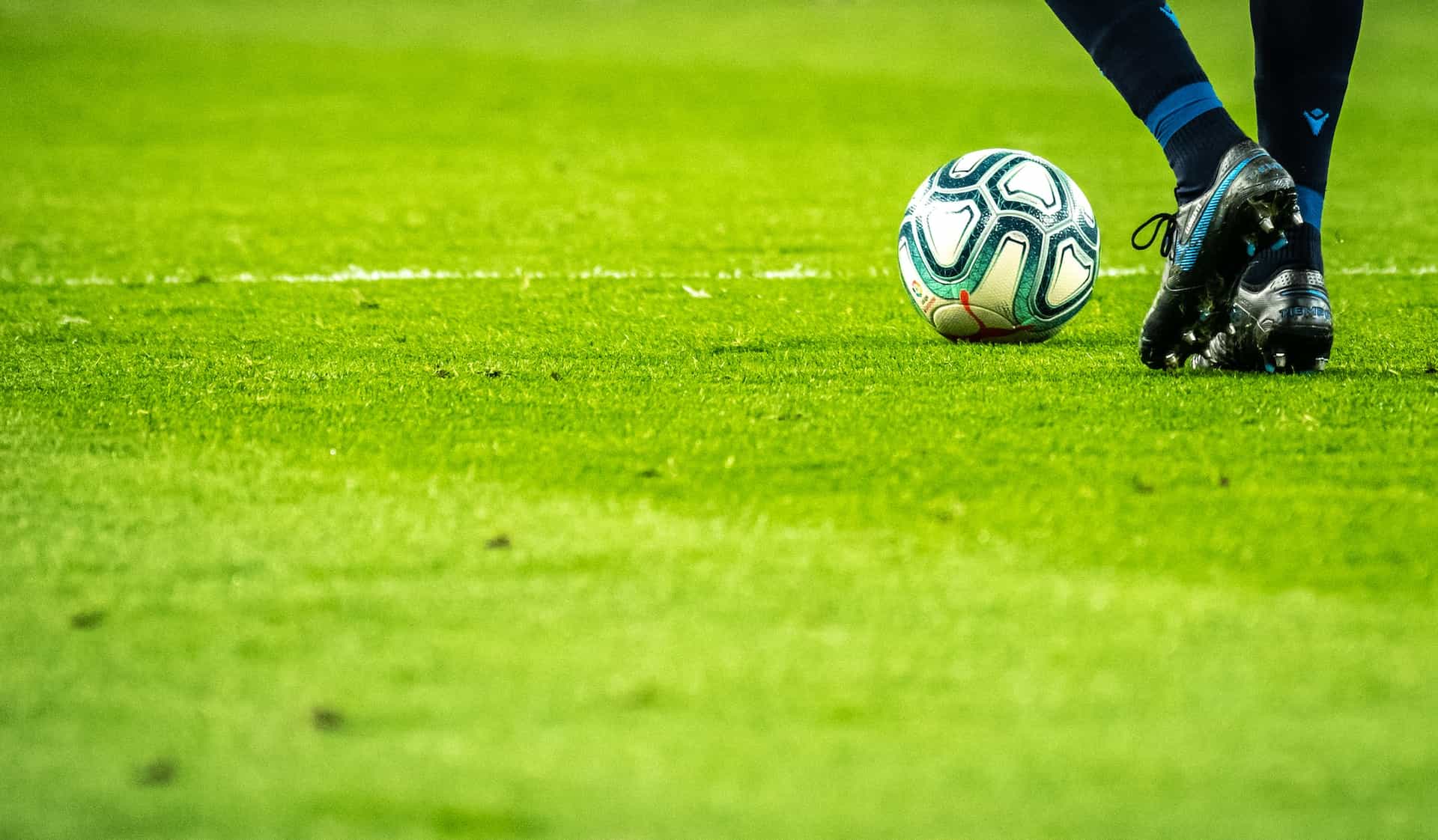 Seorang pria berlari melintasi halaman dengan bola sepak