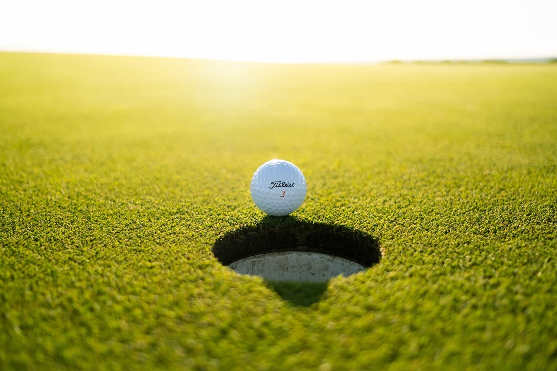 Ein Golfball liegt kurz vor dem Loch