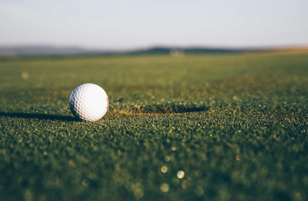 Ein Golfball liegt kurz vor dem Loch