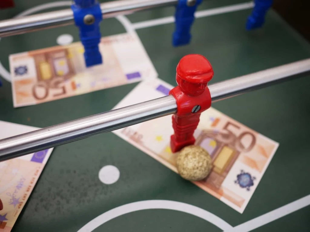 Pion bermain sepak bola meja dan uang kertas 50 euro di lapangan bermain. 