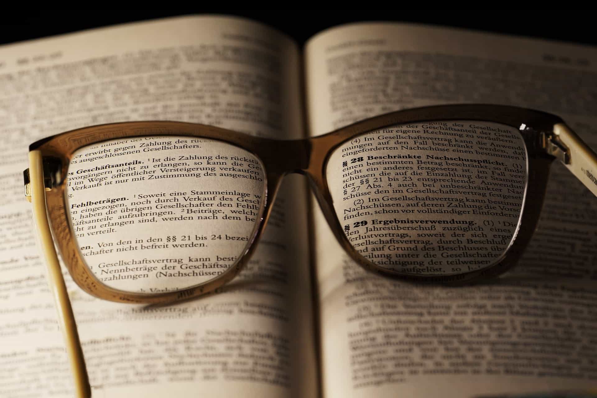 Sepasang kacamata pada buku dengan teks hukum