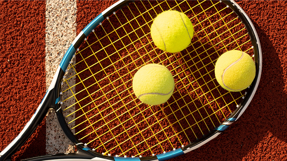 Ein Tennisspieler schlägt auf einem Sandplatz auf