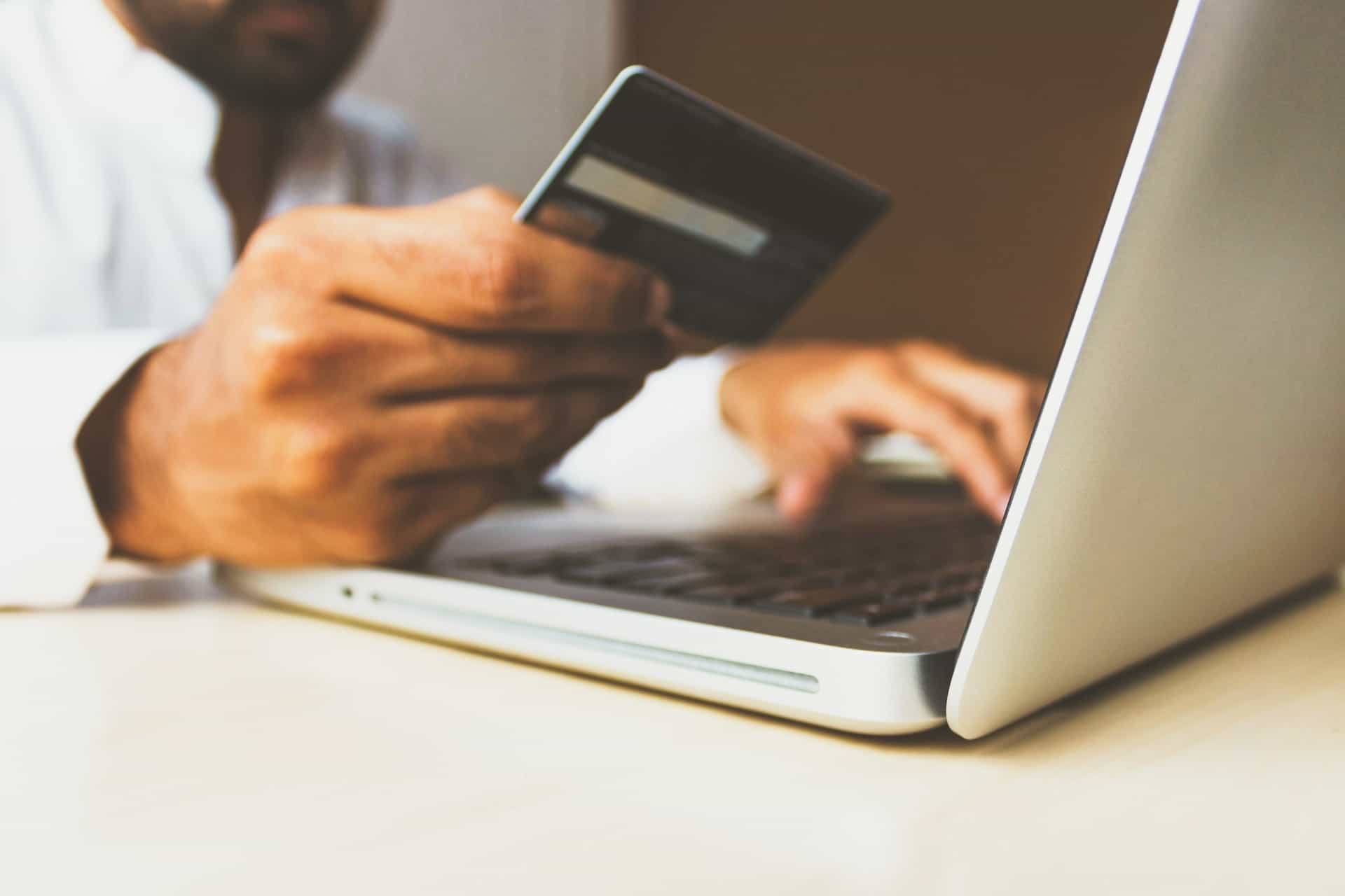 Eine Person zahlt mit Kreditkarte am Laptop