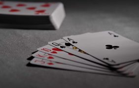 Fünf offene Pokerkarten liegen neben einem Stapel weiterer Karten auf einem Tisch.