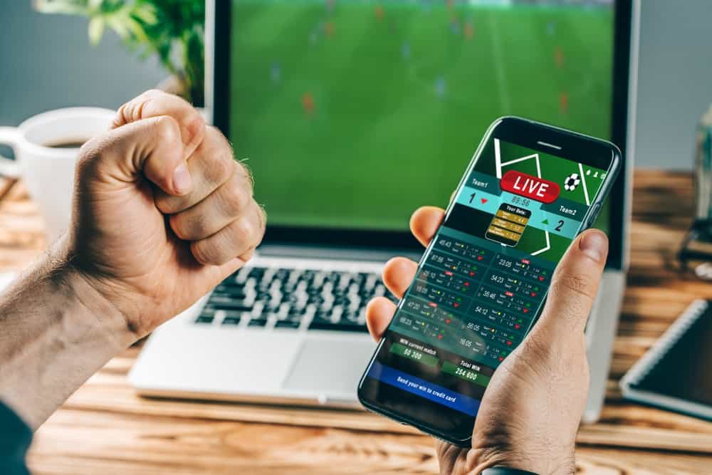 Pria dengan ponsel senang dengan kemenangan taruhan olahraga