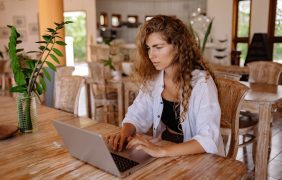 Aufnahme einer Frau, die mit ihrem Laptop in einem Café sitzt.
