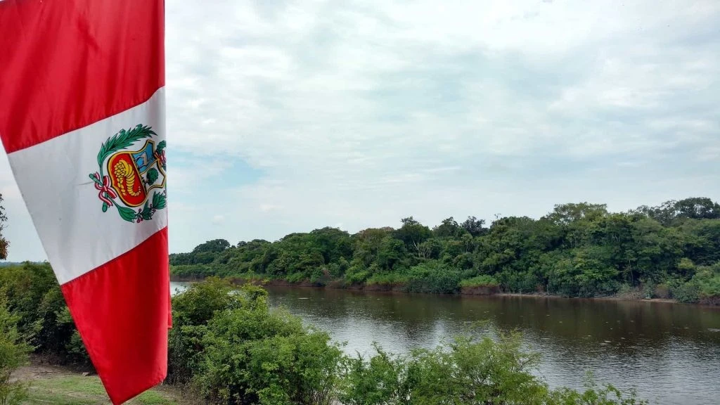 Aufnahme der peruanischen Flagge vor einem großen Fluss.