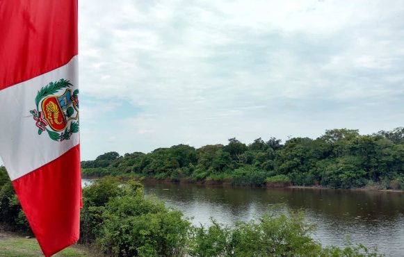 Aufnahme der peruanischen Flagge vor einem großen Fluss.