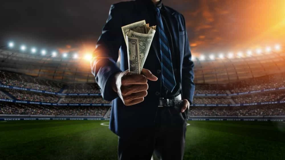 Mann mit Geld in der Hand in einem Stadion.