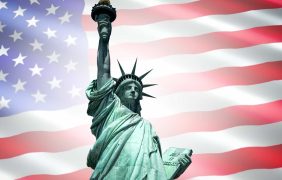 Freiheitsstatue vor einer Flagge der USA