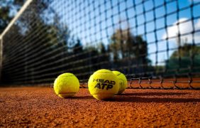 Offizielle ATP-Bälle liegen vor einem Tennisnetz