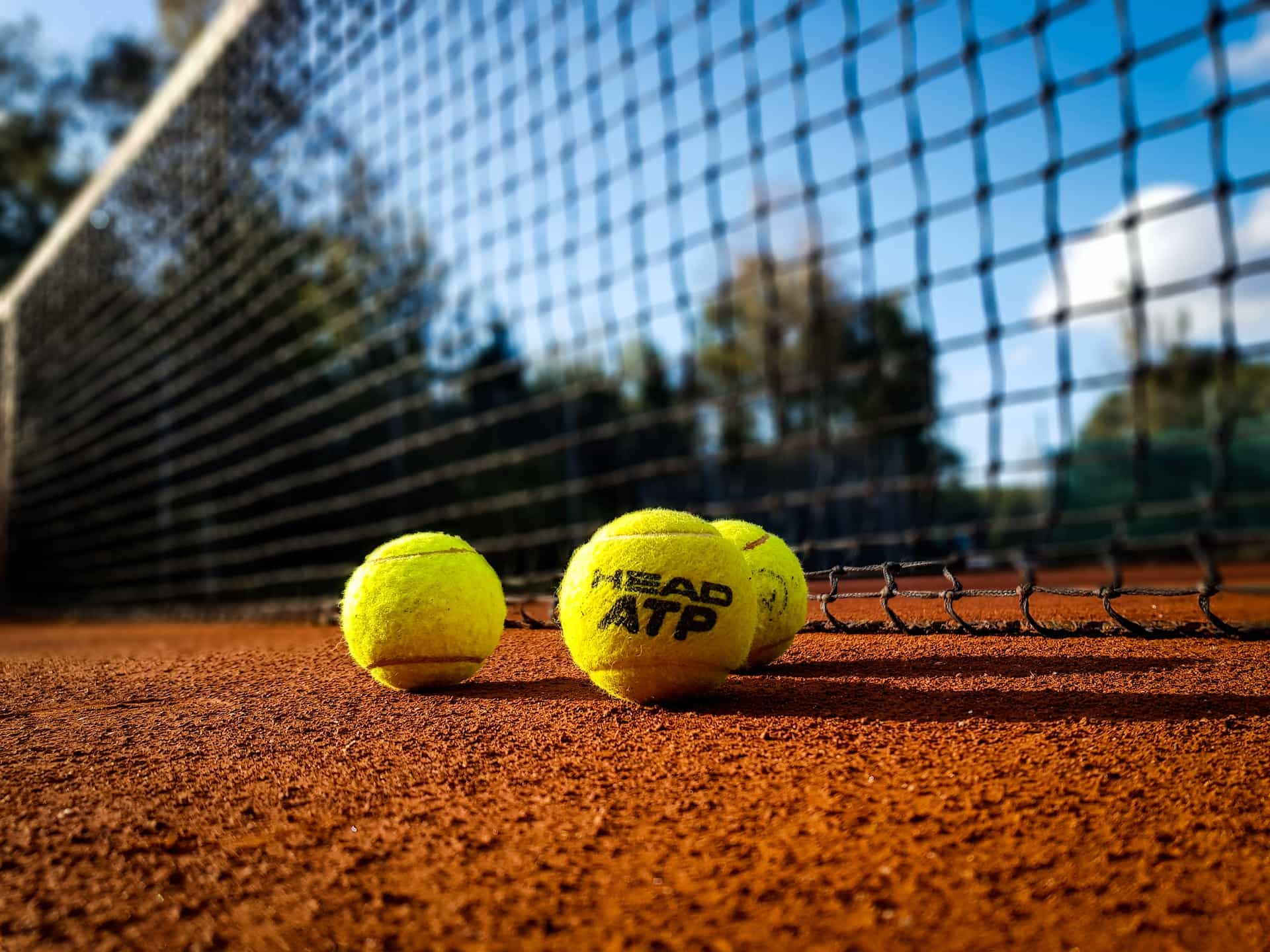 Offizielle ATP-Bälle liegen vor einem Tennisnetz