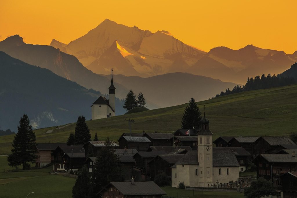 Eine kleine Ortschaft in der Schweiz mit Bergen im Hintergrund.
