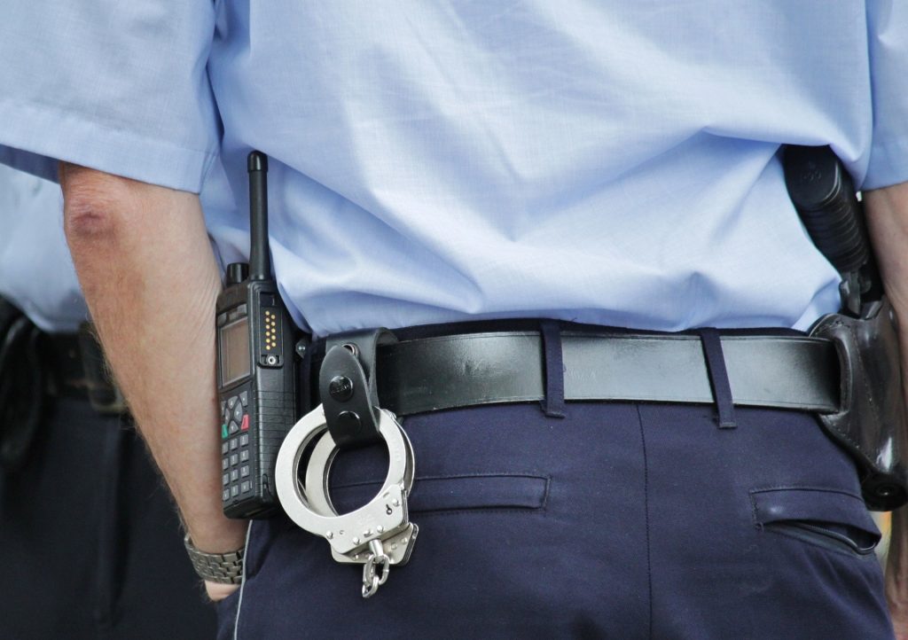 Ein Polizeibeamter, der Handschellen an seinem Gürtel trägt.
