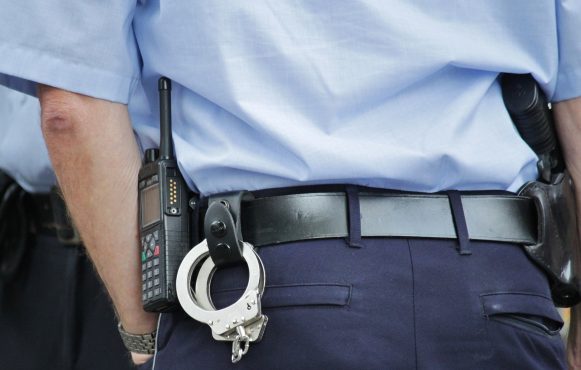 Ein Polizeibeamter, der Handschellen an seinem Gürtel trägt.