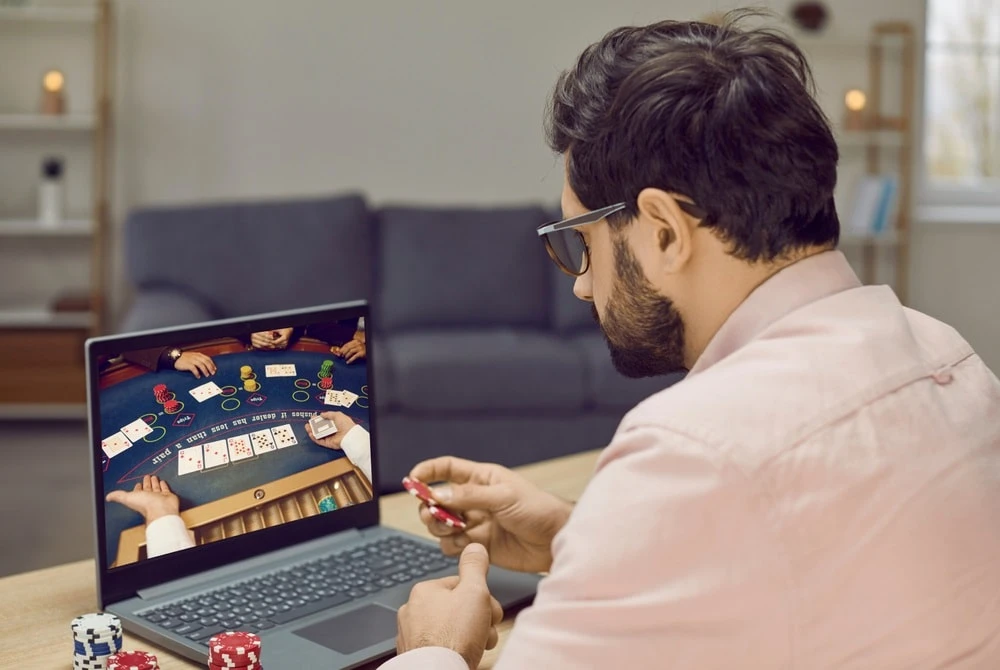 Aufnahme eines Mannes, der an seinem Laptop an Online Glücksspiel teilnimmt.