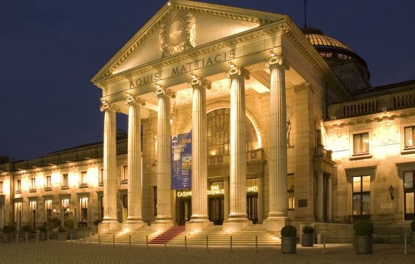 Aufnahme der Spielbank Wiesbaden mit einem sprudelnden Brunnen davor.