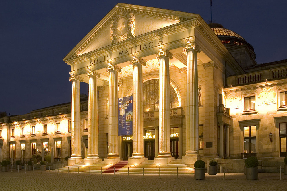 Aufnahme der Spielbank Wiesbaden mit einem sprudelnden Brunnen davor.