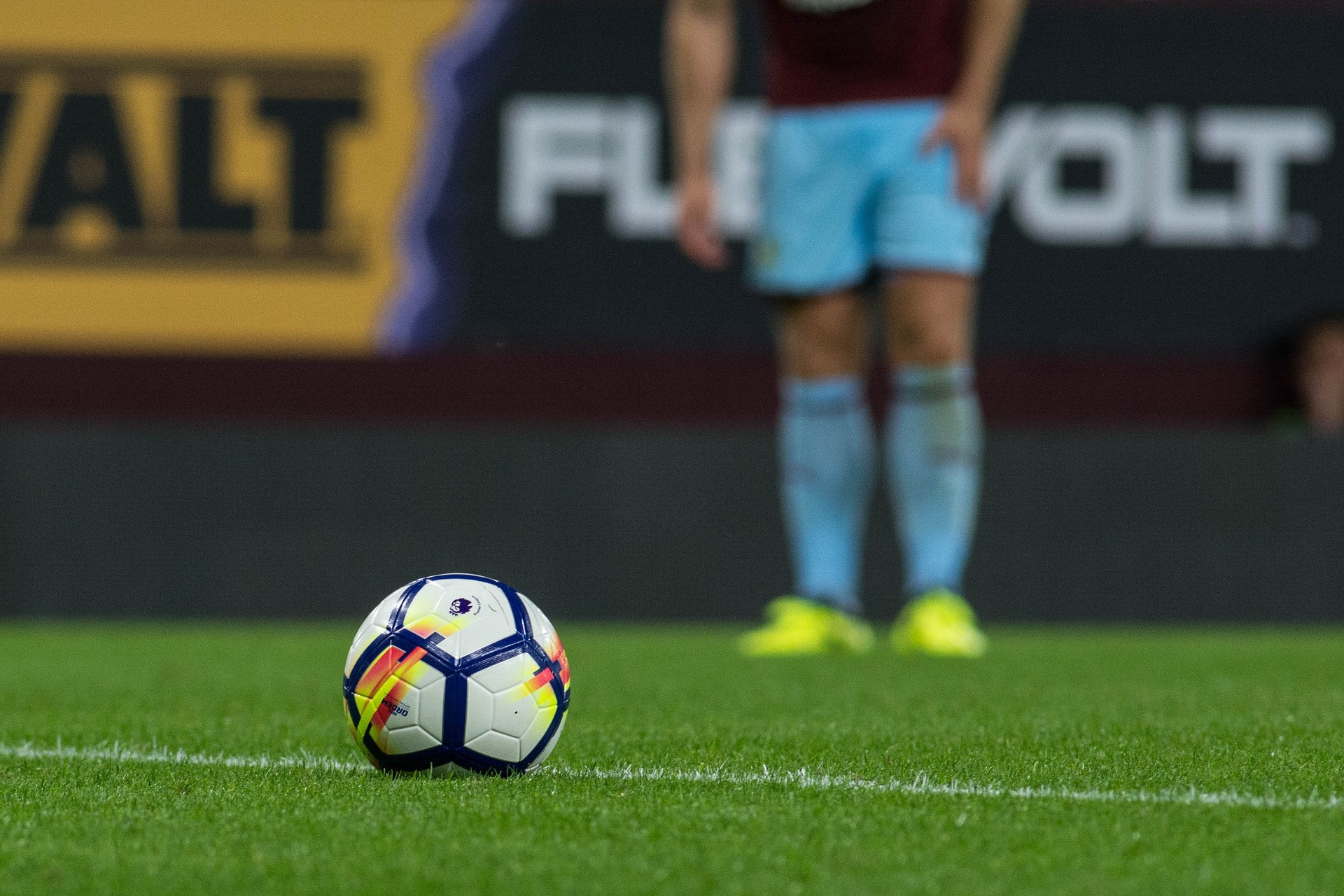 Aufnahme eines Fußballs mit einem Fußballspieler im Hintergrund.