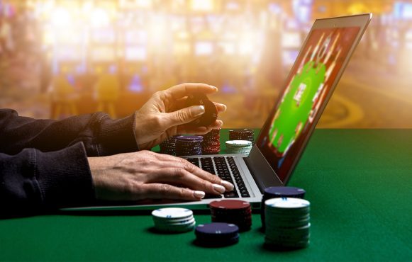 Ein Mensch sitzt an einem Pokertisch mit einem Computer.