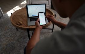 Mann vor Laptop und Smartphone mit Aktienkursen.