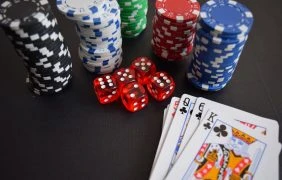Pokerkarten, Chips und Würfel auf einer schwarzen Oberfläche.